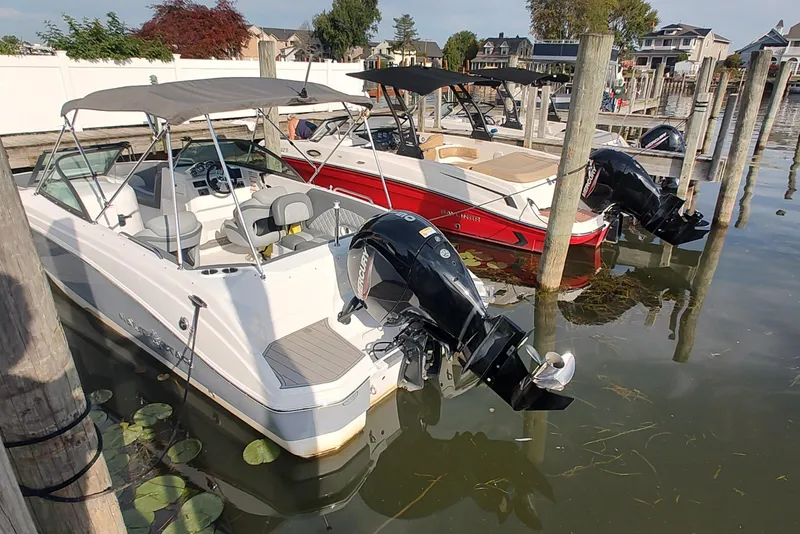 Slide: The Image of 2026 NauticStar 223 DC Deck boat docked, featuring a sleek design and powerful outboard motor. - 6