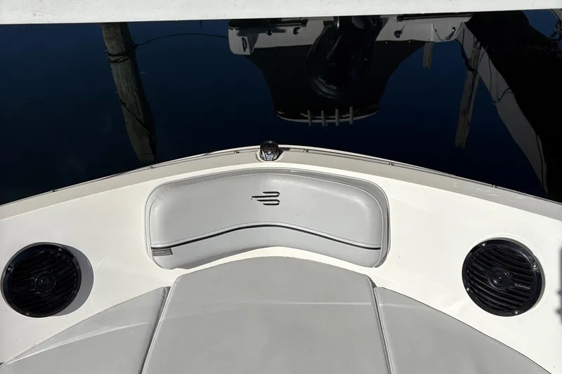 Slide: The Image of 2024 Bayliner VR6 Bowrider OB interior with seating and speakers, docked on calm water. - 8