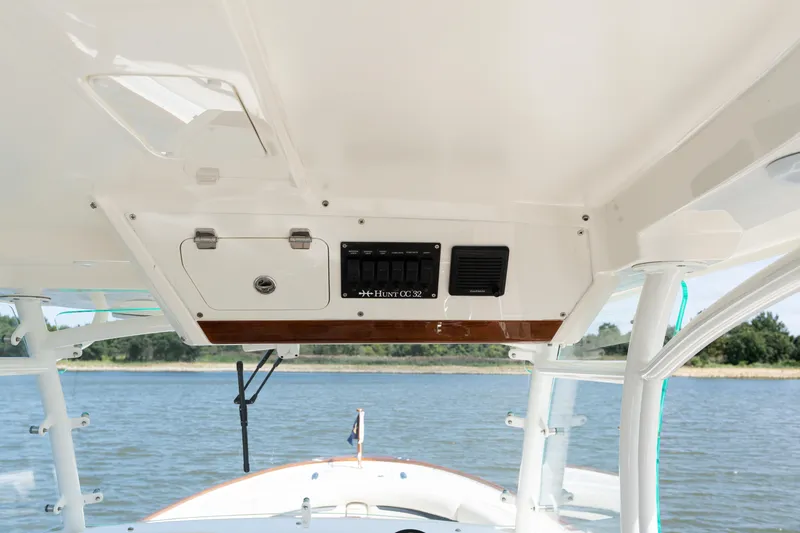 Slide: The Image of 2019 Hunt Yachts 32CC helm with control panel, overlooking serene water and shoreline. - 16