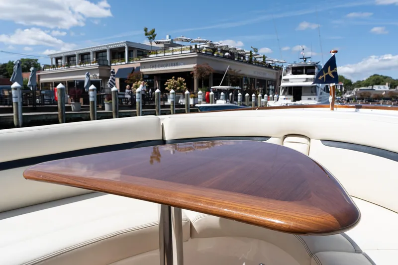 Slide: The Image of 2019 Hunt Yachts 32CC with polished wooden table, docked near waterfront restaurant. - 32