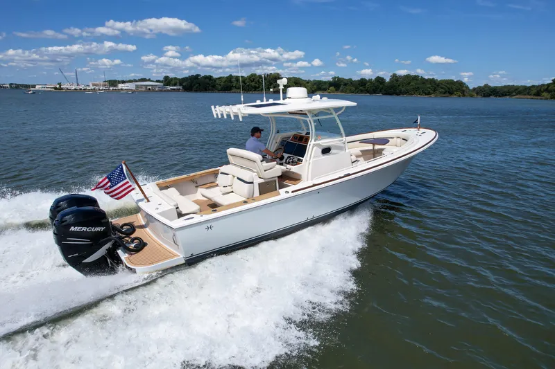 Slide: The Image of 2019 Hunt Yachts 32CC cruising on water with American flag, clear sky, and lush shoreline. - 36