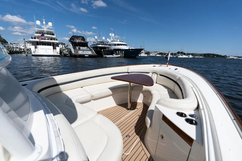 Slide: The Image of 2019 Hunt Yachts 32CC boat interior with elegant seating and table, docked near luxury yachts. - 3