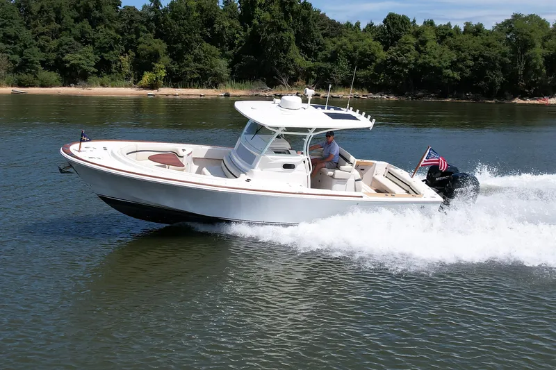 Slide: The Image of 2019 Hunt Yachts 32CC cruising on a lake with lush green shoreline. - 37