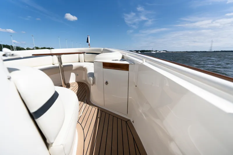 Slide: The Image of 2019 Hunt Yachts 32CC boat interior with elegant seating and wooden deck, under clear blue sky. - 5