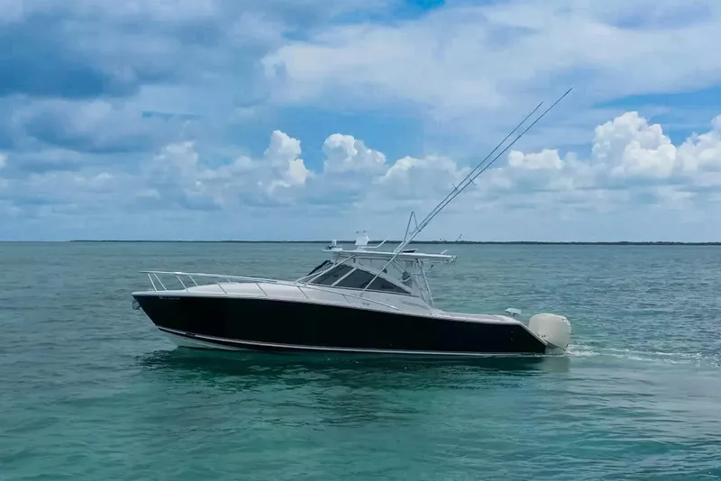 Slide: The Image of 2009 Jupiter 39 Express boat on clear turquoise water, featuring triple outboard engines. - 0