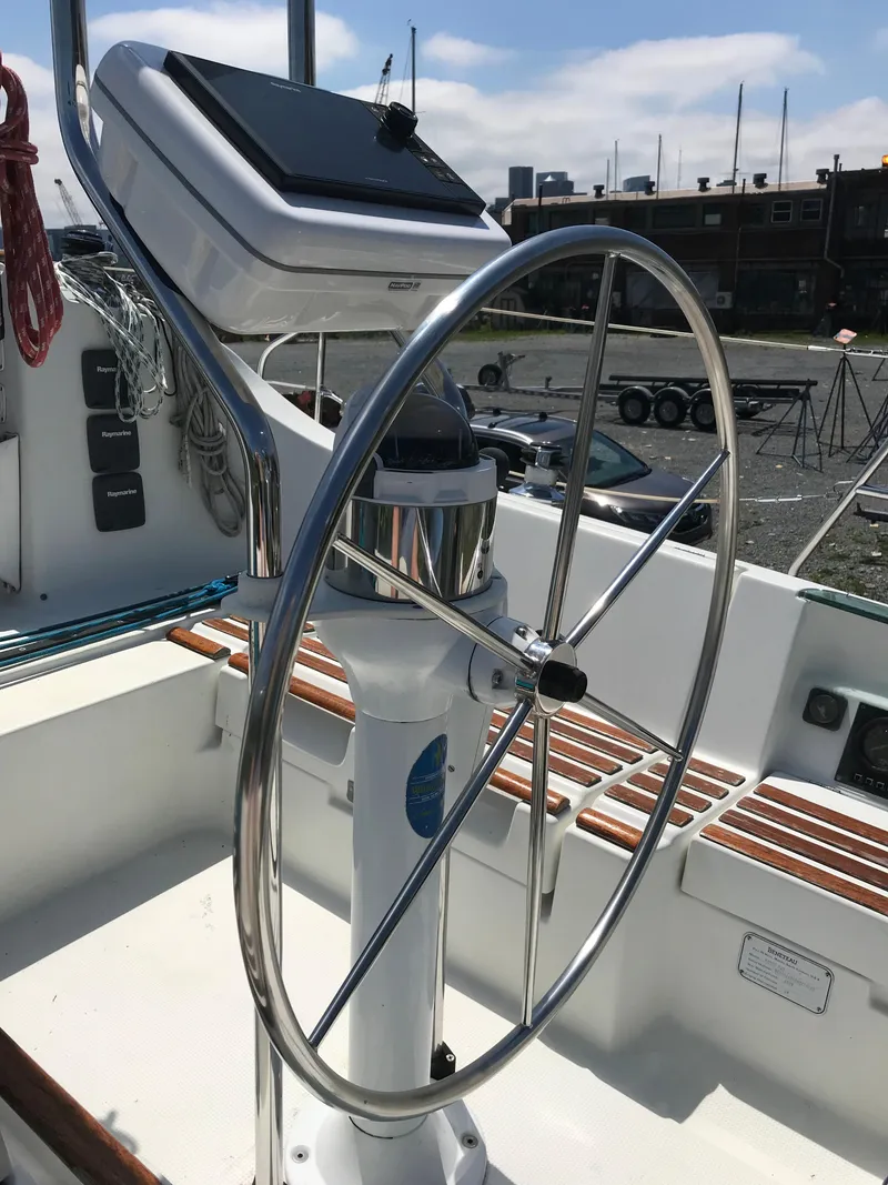 Slide: The Image of Steering wheel of a 1993 Beneteau First 310 sailboat, docked with clear skies. - 12
