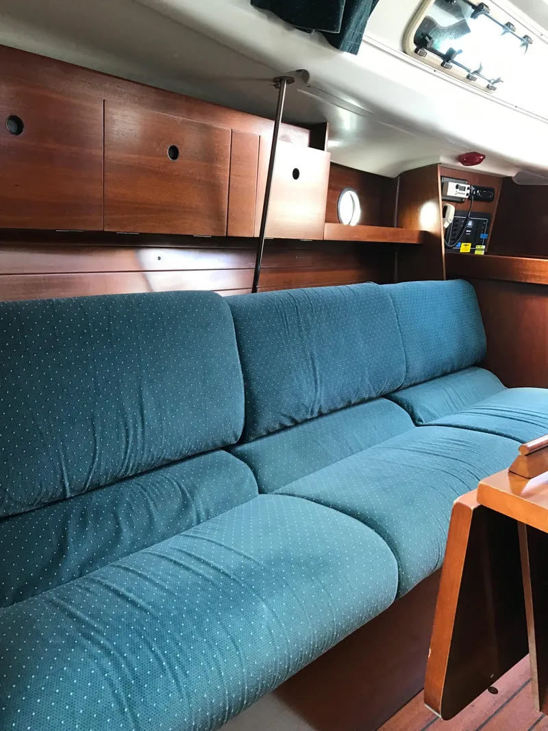 Slide: The Image of Interior of 1993 Beneteau First 310 sailboat with blue cushioned seating and wooden cabinetry. - 32