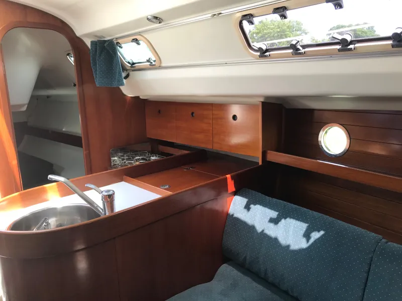 Slide: The Image of Interior of 1993 Beneteau First 310 sailboat with wooden cabinetry and compact kitchen area. - 35