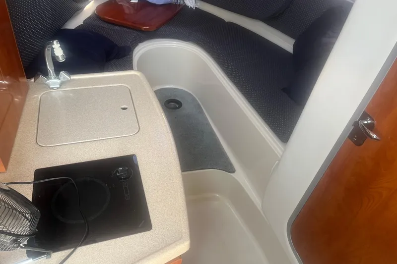 Slide: The Image of Interior of 2004 Four Winns 268 Vista boat, featuring compact kitchen and seating area. - 12