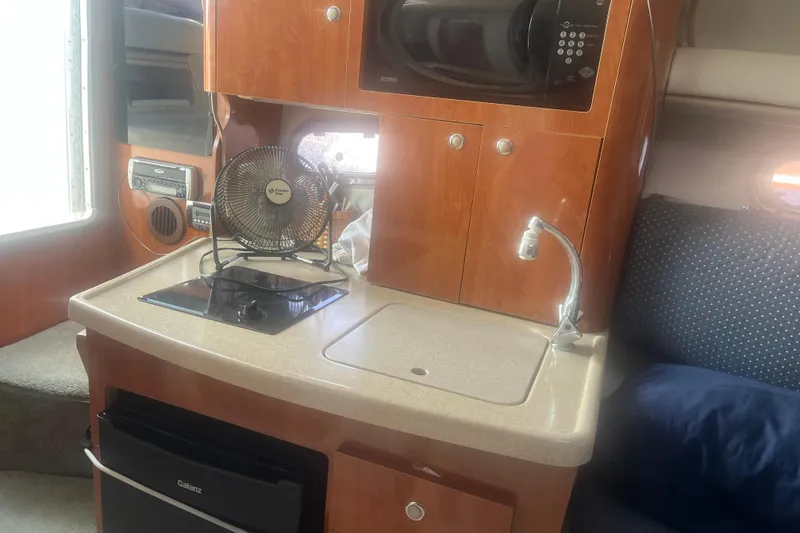 Slide: The Image of 2004 Four Winns 268 Vista boat interior with kitchenette, featuring stove, sink, and microwave. - 17