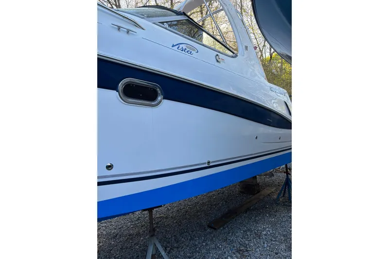 Slide: The Image of 2004 Four Winns 268 Vista boat side view, white and blue hull, on gravel. - 31