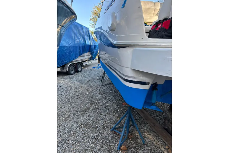 Slide: The Image of 2004 Four Winns 268 Vista boat on stands, gravel lot, blue and white hull. - 32