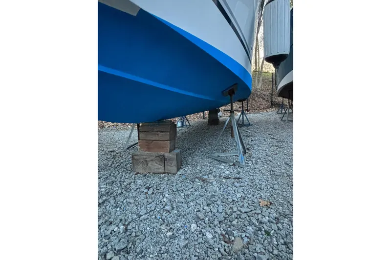 Slide: The Image of 2004 Four Winns 268 Vista boat on stands, gravel ground, blue hull. - 43