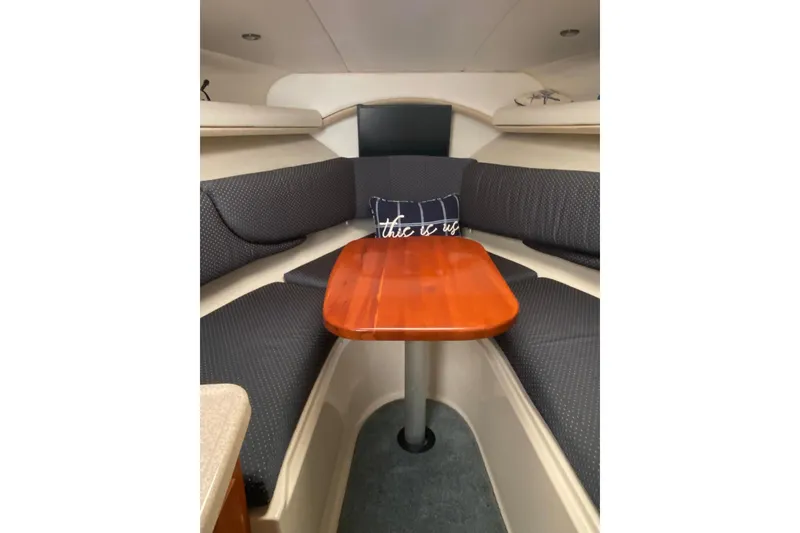 Slide: The Image of 2004 Four Winns 268 Vista cabin interior with wooden table and cushioned seating. - 52