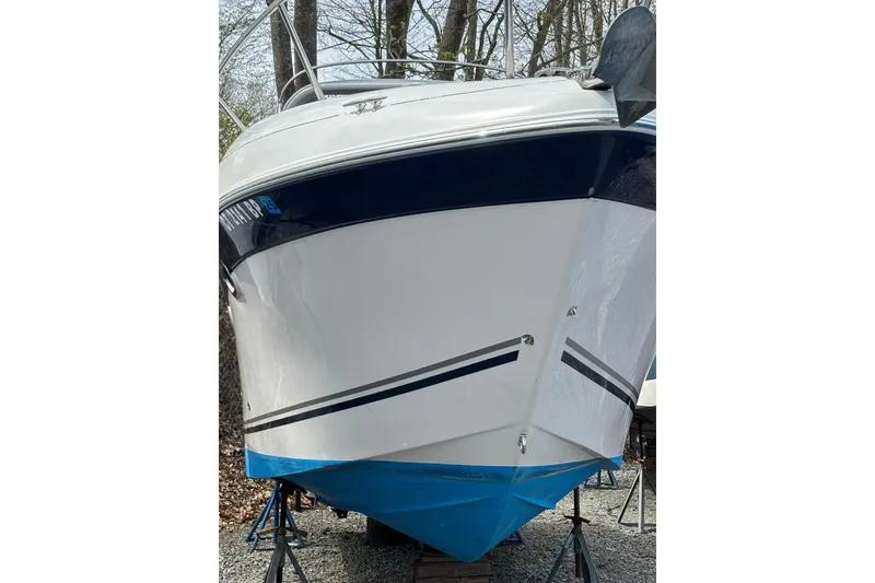 Slide: The Image of 2004 Four Winns 268 Vista boat on stands, white and blue hull, outdoors. - 54