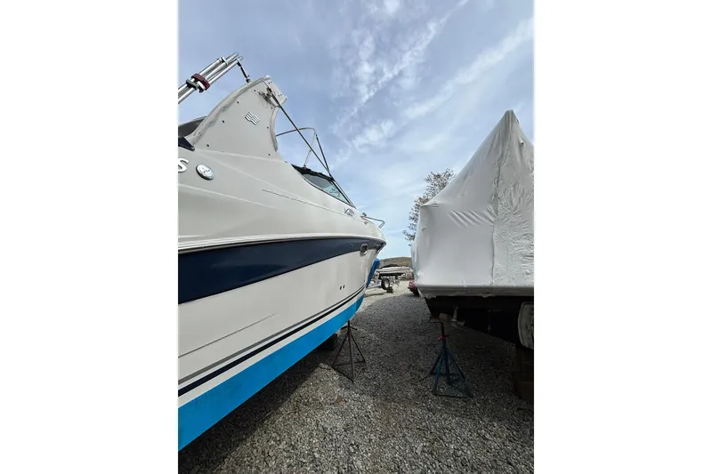 Slide: The Image of 2004 Four Winns 268 Vista boat on stands beside a covered vessel. - 55