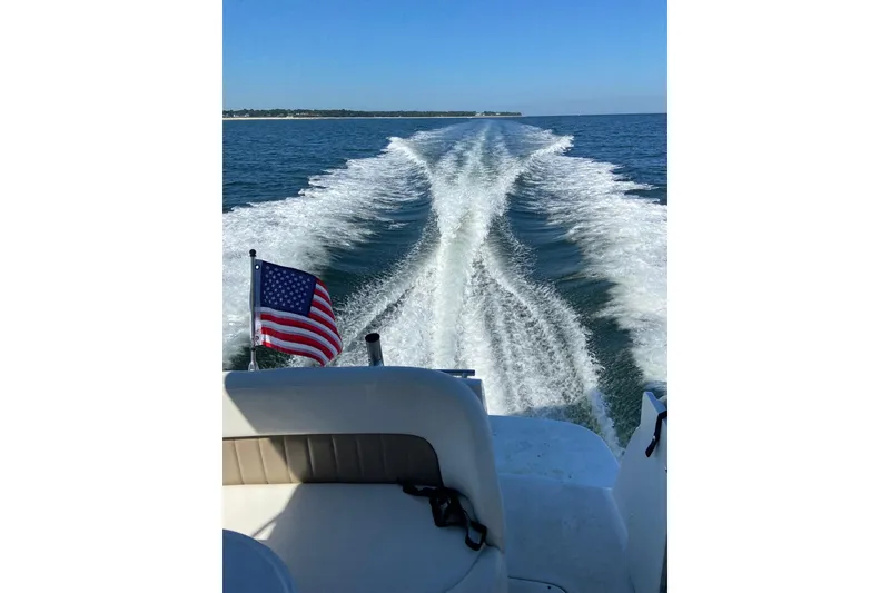 Slide: The Image of 2004 Four Winns 268 Vista boat cruising with American flag, leaving wake on open water. - 56