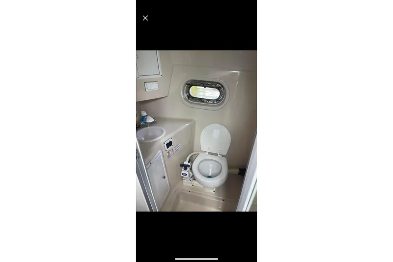 Slide: The Image of 2004 Four Winns 268 Vista boat bathroom with toilet, sink, and porthole window. - 62