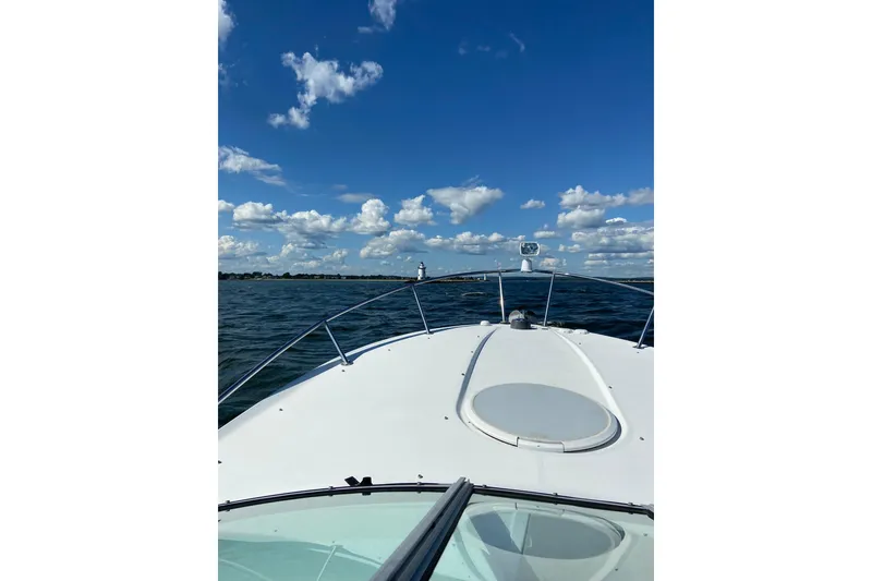Slide: The Image of 2004 Four Winns 268 Vista boat cruising on open water under a clear blue sky. - 63