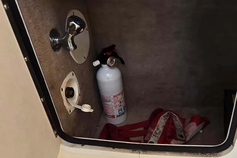 Slide: The Image of Storage compartment in a 1998 Sea Ray 330 Sundancer with fire extinguisher and safety equipment. - 15