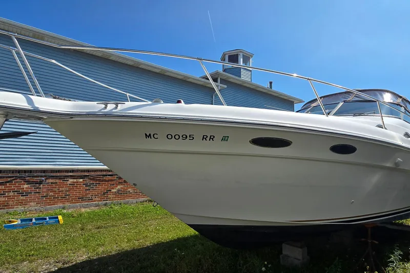 Slide: The Image of 1998 Sea Ray 330 Sundancer boat docked near a blue building under clear sky. - 2