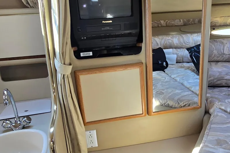 Slide: The Image of 1998 Sea Ray 330 Sundancer cabin with TV, mirror, and cozy bed. - 22