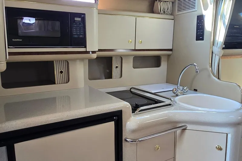 Slide: The Image of 1998 Sea Ray 330 Sundancer kitchen with microwave, sink, and storage cabinets. - 25