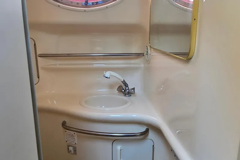Slide: The Image of 1998 Sea Ray 330 Sundancer bathroom with sink, mirror, and porthole window. - 27