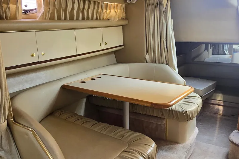 Slide: The Image of 1998 Sea Ray 330 Sundancer cabin interior with beige seating and table. - 29
