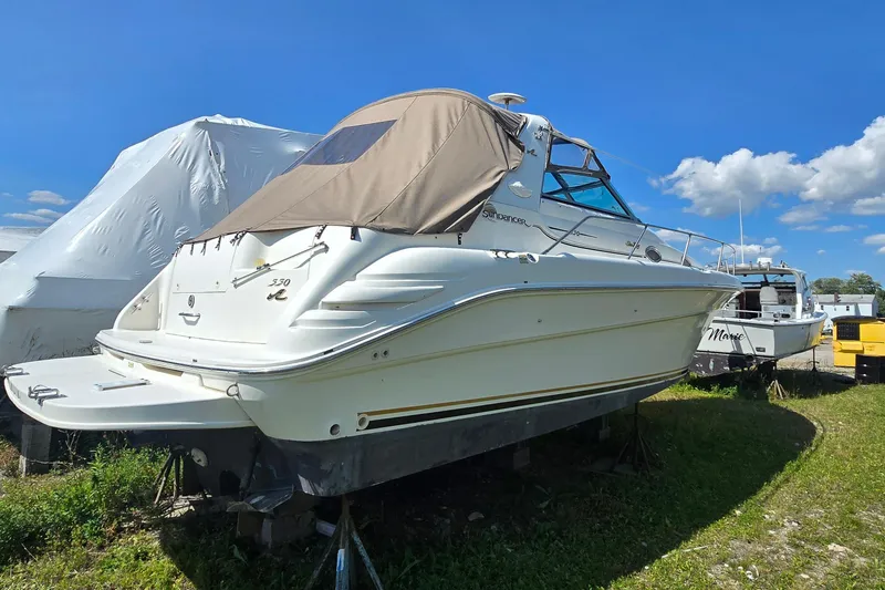 Slide: The Image of 1998 Sea Ray 330 Sundancer boat on land, covered, under clear blue sky. - 3