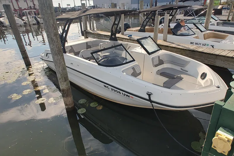 Slide: The Image of 2023 Bayliner VR6 Bowrider OB docked at marina, featuring sleek design and spacious seating. - 2