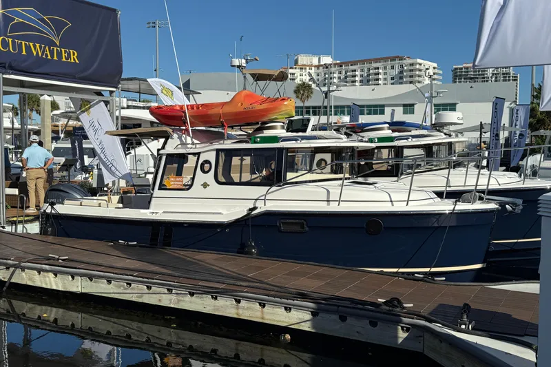 The Image of 2026 Ranger Tugs R-25 boat docked at marina, featuring sleek design and vibrant kayak on top. - 0