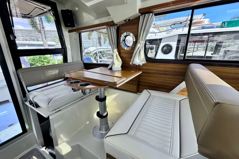Slide: The Image of Interior of 2026 Ranger Tugs R-25, featuring a cozy dining area with wood accents. - 11