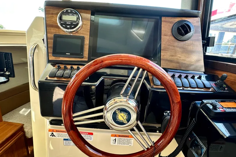 Slide: The Image of 2026 Ranger Tugs R-25 helm with wooden steering wheel and modern control panel. - 14