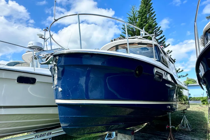 Slide: The Image of 2026 Ranger Tugs R-25 boat with blue hull, docked under a clear sky. - 2