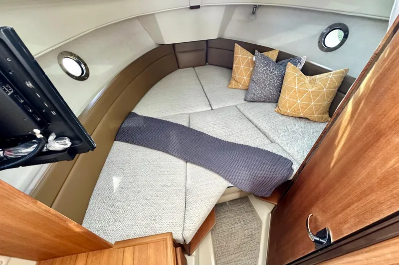 Slide: The Image of 2026 Ranger Tugs R-25 cabin interior with cozy bedding and decorative pillows. - 25