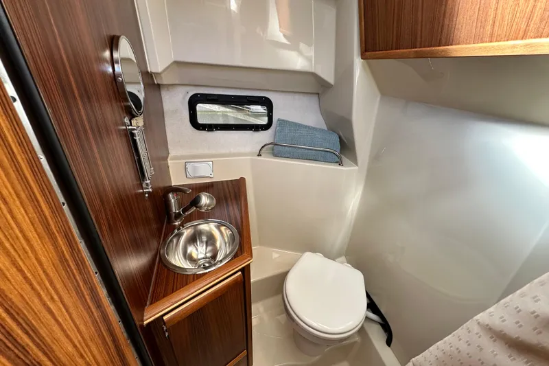 Slide: The Image of 2026 Ranger Tugs R-25 boat bathroom with sink, toilet, and wooden cabinetry. - 31