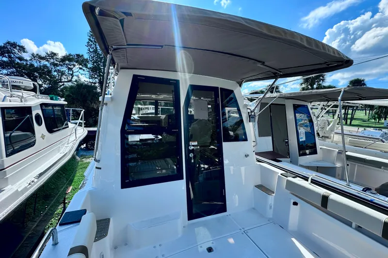 Slide: The Image of 2026 Ranger Tugs R-25 boat with canopy, docked under a clear blue sky. - 37