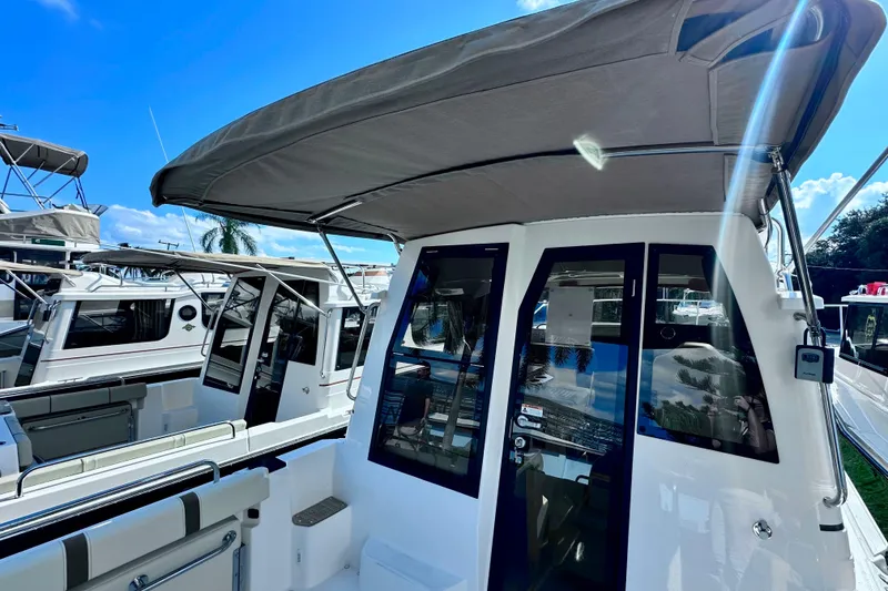 Slide: The Image of 2026 Ranger Tugs R-25 boat with canopy, docked under clear blue sky. - 39