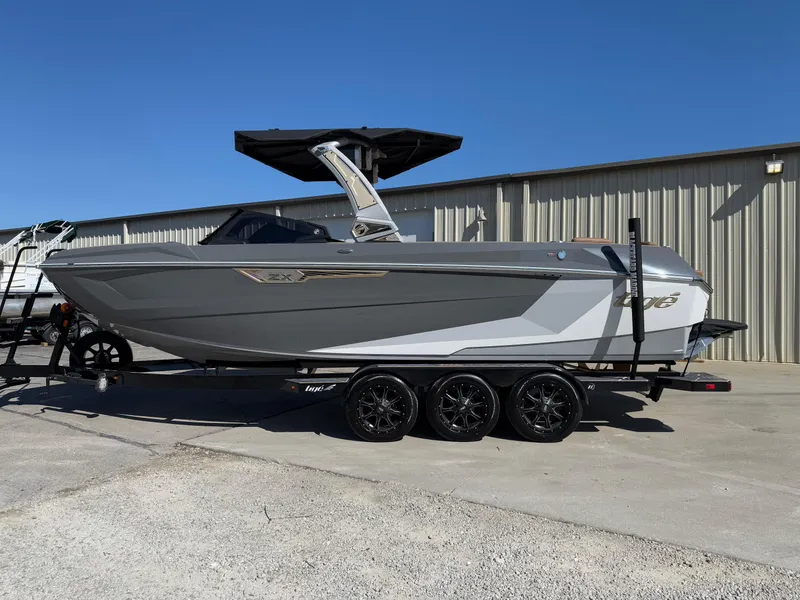 The Image of 2025 Tigé Ultré 25ZX boat on trailer, parked outdoors, clear sky background. - 0