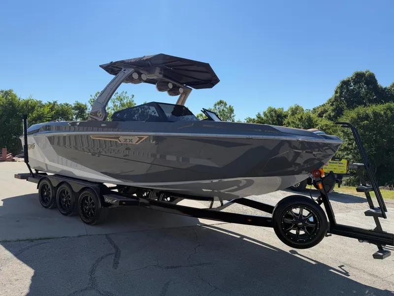 Slide: The Image of 2025 Tigé Ultré 25ZX boat on trailer, sleek design, parked outdoors. - 2