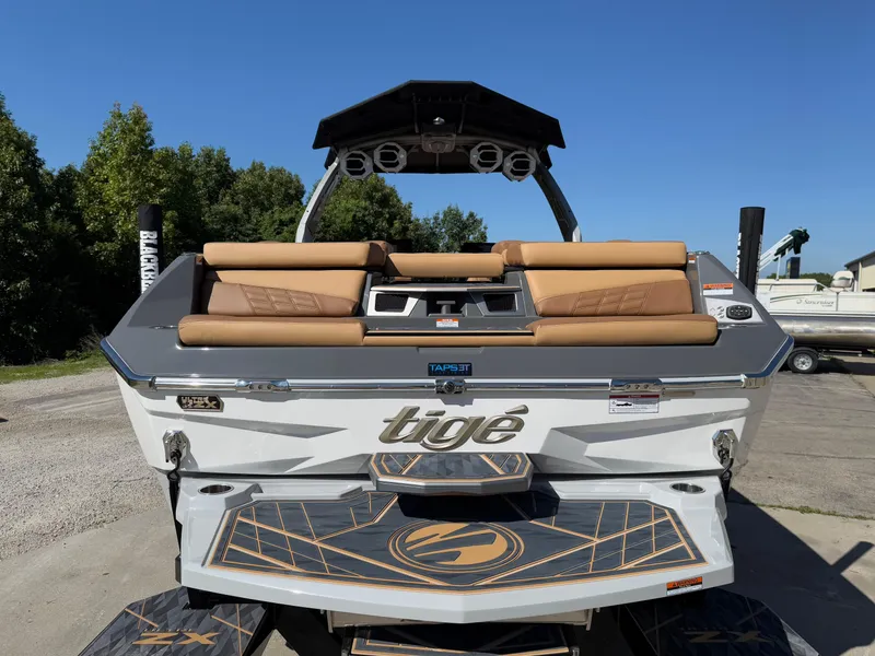 Slide: The Image of 2025 Tigé Ultré 25ZX boat with tan seating and sleek design, parked outdoors. - 5