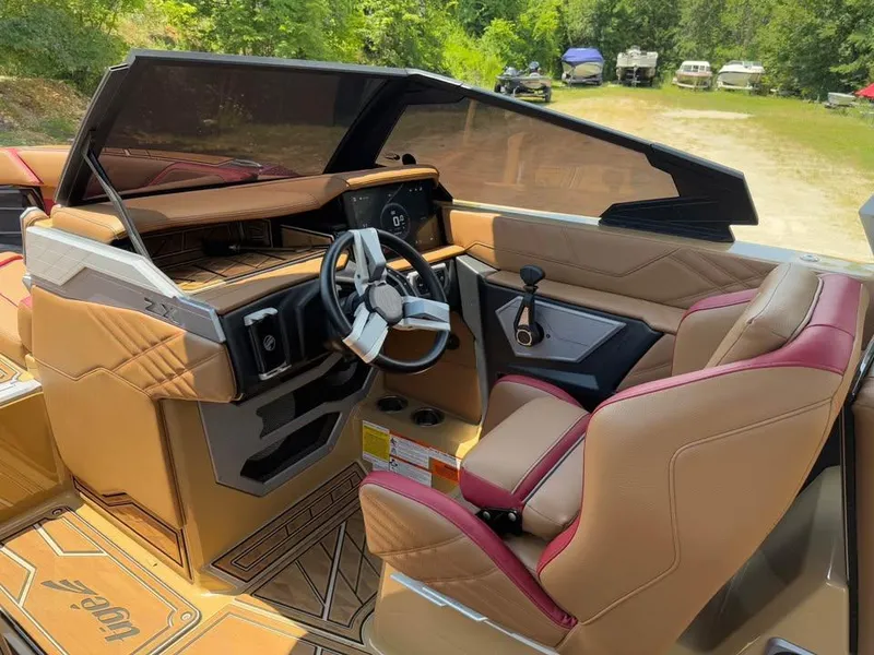 Slide: The Image of 2024 Tigé Ultré 25ZX boat interior with tan and red seating, modern dashboard, and steering wheel. - 10