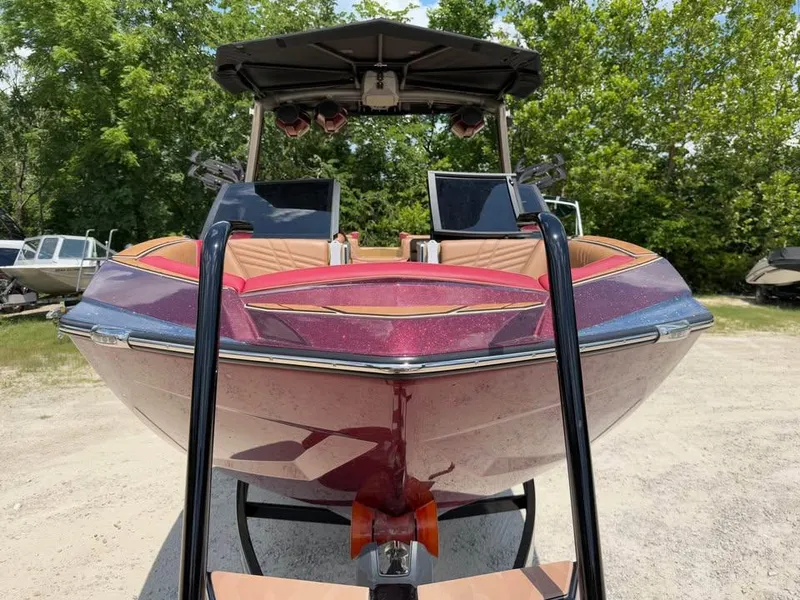 Slide: The Image of 2024 Tigé Ultré 25ZX boat with vibrant exterior, parked outdoors, surrounded by greenery. - 2