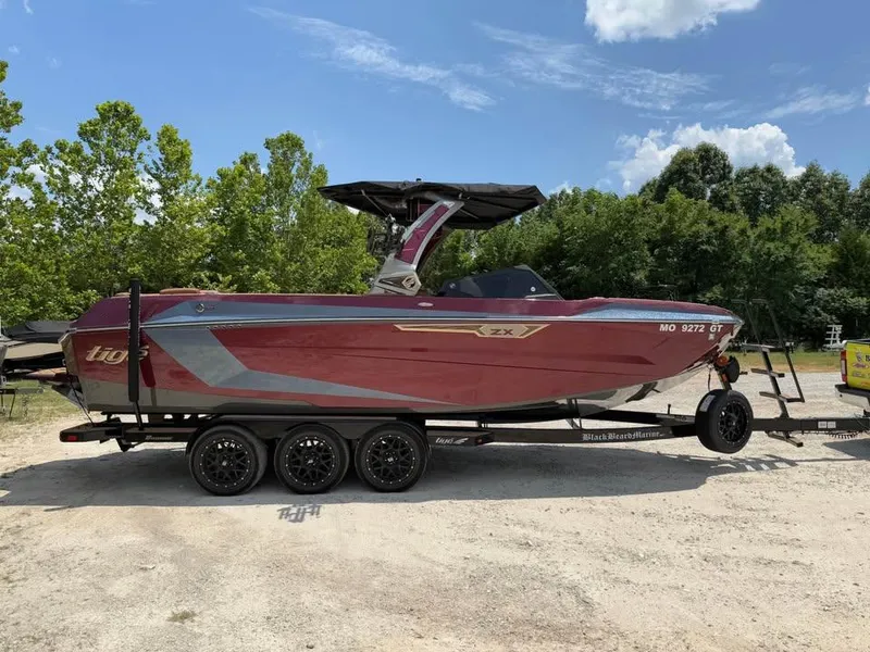 Slide: The Image of 2024 Tigé Ultré 25ZX boat on trailer, parked outdoors with trees in background. - 4