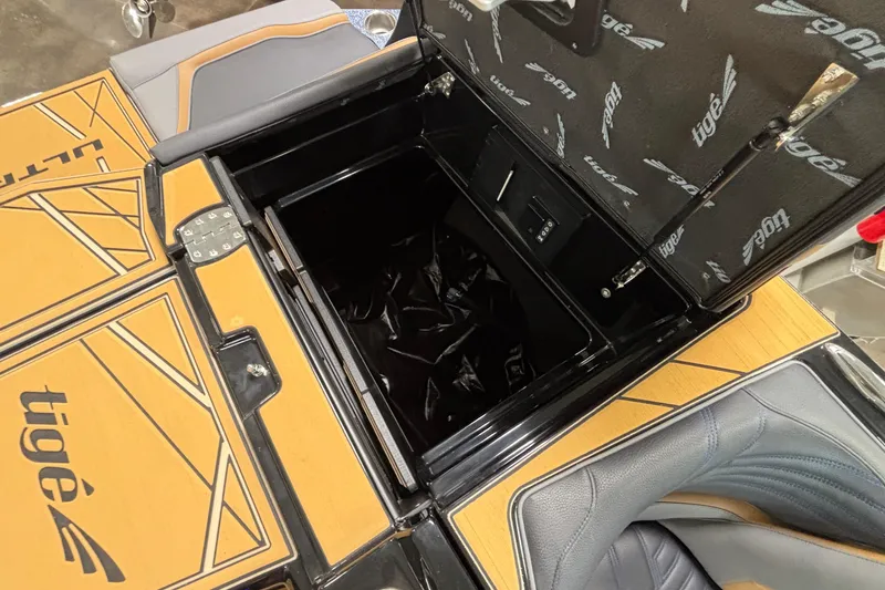 Slide: The Image of 2026 Tigé Ultré 25ZX boat storage compartment with open lid and branded interior. - 27