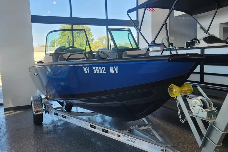 Slide: The Image of 2023 Lowe boat on trailer in showroom, blue exterior, registration NY 3832 MV. - 3