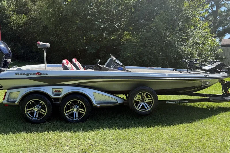 Slide: The Image of 2018 Ranger Z521L boat on trailer, parked on grass, surrounded by trees. - 1