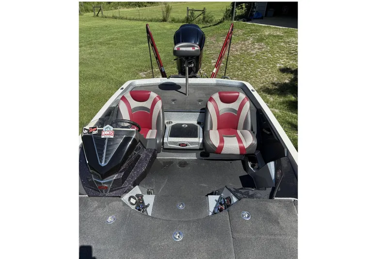 Slide: The Image of 2018 Ranger Z521L boat interior with red and gray seats, parked on grass. - 2