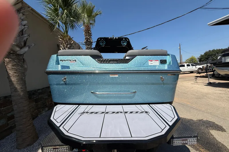 Slide: The Image of 2024 Moomba Tykon boat rear view with Raptor engine, parked outdoors. - 7